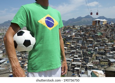 Brazilian football player standing in Brazil flag t-shirt holding soccer ball in front of favela slum background in Rio de Janeiro
