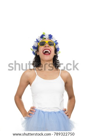Brazilian girl is laughing a lot and with her hands on her waist. Black teenager is dressed for Carnival. Crown and necklace of Hawaiian flowers. Yellow sunglasses. Concept of Mardi Gras, Travel