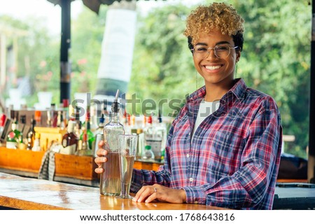 brazilian hispanic mixed race woman barman making beverage alcoholic drink at beach shack in tropic