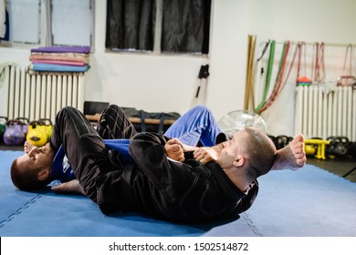 Brazilian Jiu Jitsu BJJ Jiujitsu Training Sparring Athlete Fighter Applying Arm Bar Armbar Submission On His Opponent Technique Practice Wearing Kimono Gi