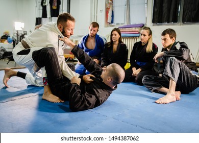 Brazilian Jiu JItsu BJJ professor teaching technique from the guard position to his students in training class at the martial arts academy - Powered by Shutterstock