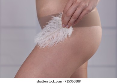 Brazilian laser hair removal bikini line. Waxing For woman. Woman touching her smooth perfect skin after beauty treatment with feather