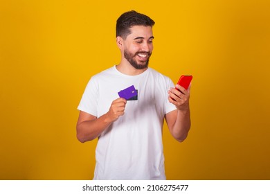 Brazilian Latin American Man, Performing By His Cell Phone, Using Credit Card, Online Shopping Concept