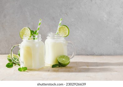 Brazilian Lemonade, Refreshing Creamy Lemonade or Limeade with Lime Slices and Mint on Bright Background