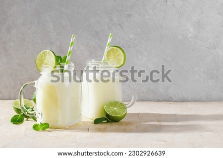 Brazilian Lemonade, Refreshing Creamy Lemonade or Limeade with Lime Slices and Mint on Bright Background