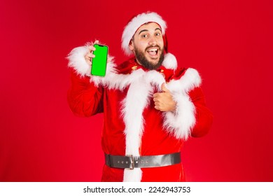 brazilian man, dressed in santa claus clothes, holding smartphone with green chroma screen - Powered by Shutterstock