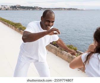 Brazilian man practicing capoeira near coastal promenade with scenic ocean view - Powered by Shutterstock