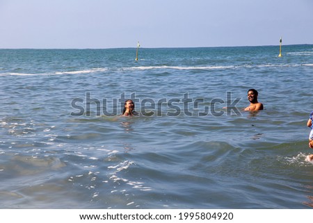 Brazilian man and woman on the beach in Sorocotuba, Guarujá, São Paulo, Brazil. Black man and white woman. into the sea with waves