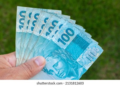 brazilian money in hand with green background