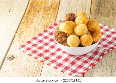 Brazilian Salgadinhos De Festa, Traditional Party Snack Mix With Coxinha, Kibe, And Other Fried Snacks Over Wooden Table In A White Container