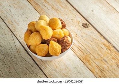 Brazilian Salgadinhos De Festa, Traditional Party Snack Mix With Coxinha, Kibe, And Other Fried Snacks Over Wooden Table In A White Container