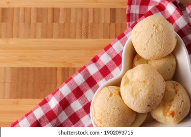 Brazilian snack cheese bread in a heart shaped bowl "Pao de queijo" in a wooden background.  Small bacon cheese rolls. Also known in Latin America as Chipa, Pan de Bono and Pan de Yuca. Copy space.
