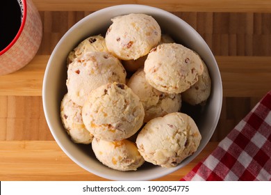 Brazilian snack cheese bread in a white bowl. "Pao de queijo" with coffee in a wooden background.  Small bacon cheese rolls. Also known in Latin America as Chipa, Pan de Bono and Pan de Yuca. 