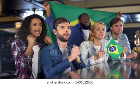 Brazilian soccer fans with flag cheering for national team, hoping for victory - Powered by Shutterstock