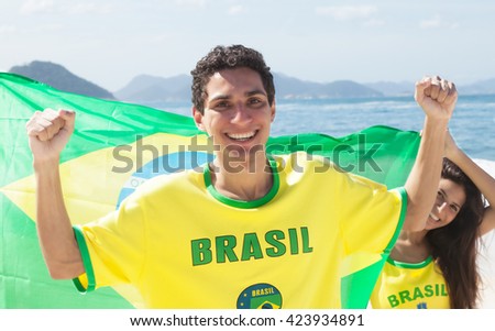 Brazilian sport fans with jersey and flag and Copacabana beach of Rio de Janeiro in the background