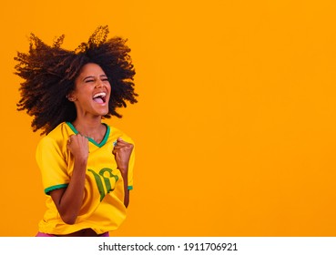Brazilian supporter. Brazilian woman fan celebrating on soccer or football match on yellow background. Brazil colors.
