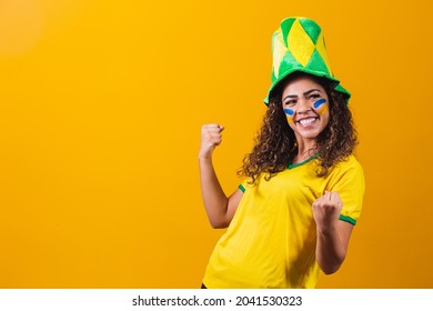 Brazilian supporter. Brazilian woman fan celebrating on soccer or football match on yellow background. Brazil colors.
