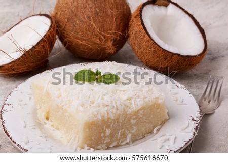 Brazilian traditional dessert: sweet couscous (tapioca) pudding (cuscuz doce) with coconut on plate on marble table. Selective focus