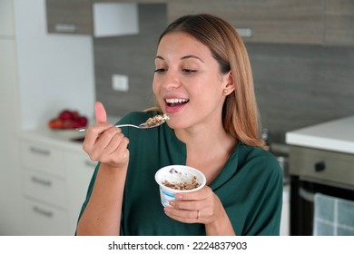 Brazilian woman eating white yogurt with granola at home