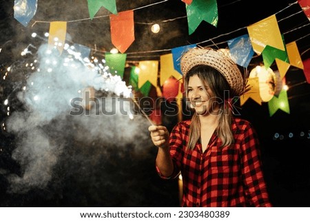 Brazilian woman joyfully celebrates Festa Junina with fireworks, adding sparkle and excitement to the festive ambiance