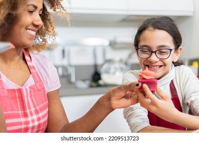 Brazilian Woman Showing To His Daughter How To Decorating A Cup Cake. Mom And Daughter Making At Home American Desserts Together