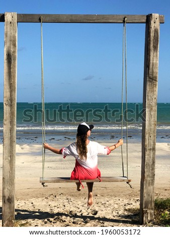 Brazilian woman sitting on a tourist swing on the beach of Sao Miguel dos Milagres, Alagoas