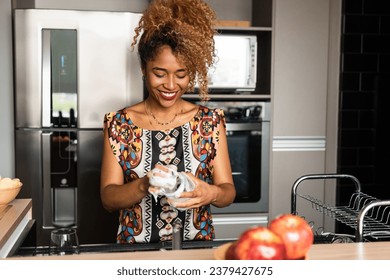 Brazilian woman washes dishes in kitchen at home