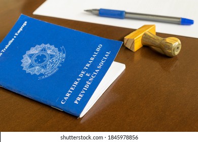 Brazilian Work Card (carteira de trabalho) with stamp, pen and paper on the table. Employment contract concept. Portuguese text "Work and Social Security Card". contract Brasil. inss