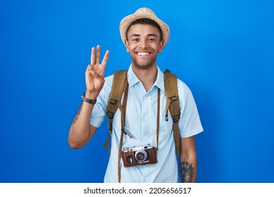 Brazilian Young Man Holding Vintage Camera Showing And Pointing Up With Fingers Number Three While Smiling Confident And Happy. 