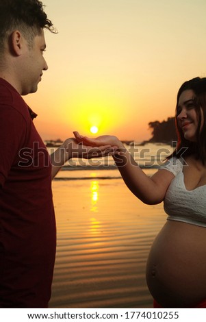 Brazilian young pregnant woman on the beach at sunrise with her husband