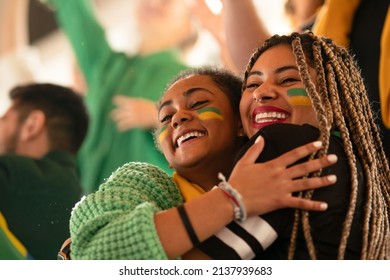 Brazilian young sisters football fans celebrating their team's victory at stadium. - Shutterstock ID 2137939683