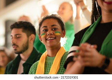 Brazilian young sisters football fans supporting their team at stadium.