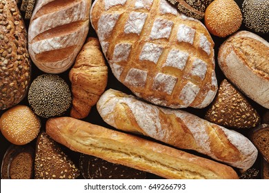 Bread background, top view of white, black and rye loaves on black