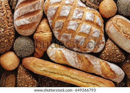 Bread background, top view of white, black and rye loaves on black