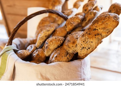 Bread in a basket in the wooden house interior. Assorted baking in a metal basket. Place for recipe and text. Background with rolling pin and flour. Rye bread and baguette with seeds. Buckwheat bread - Powered by Shutterstock