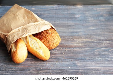 Bread In A Brown Paper Bag On A Wooden Table.