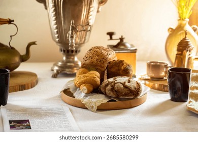 Bread and buns in a plate on a table against the background of a samovar and light from a window. Retro, close-up