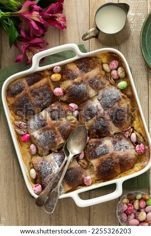 Bread and butter hot cross buns pudding decorated with colorful candy eggs. wooden background, top view