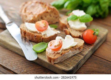 Bread With Cheese, Cherry Tomato And A Basil Leaves On Wooden Cutting Board Closeup 