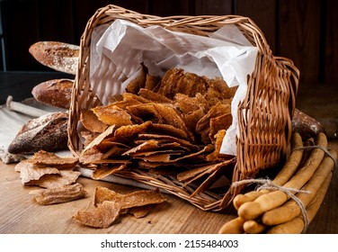 Bread chips. Basket with chips. Scattered crispy pastries. Chips in a wooden basket