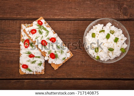 Bread with cottage cheese and chili pepper, with a bowl of cottage cheese with greens on a wooden background. Proper nutrition. Breakfast.