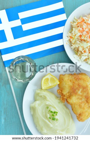 Bread crumbed cod fish and garlic dip, known as skordalia, traditional Greek dish and Greek flag on turquoise table