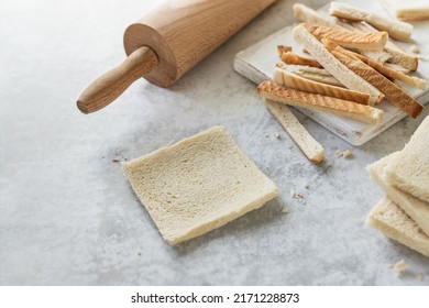 Bread Crust Pieces Freshly Cut, Toast Bread Slice Thinned With Wooden Roller Pin On The Table; Cooking At Home - French Toast Rolls In The Making