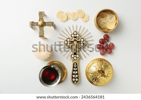 Bread, cup of wine, grapes, candle and cross on white background, top view