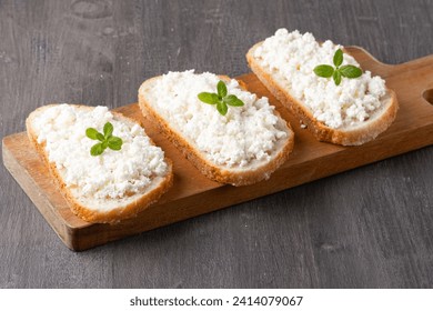 Bread with curd cheese on wooden board.