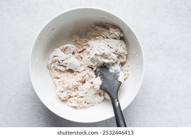 Bread dough being mixed in a ceramic bowl, Beet Focaccia dough in a white bowl, process of making pink focaccia