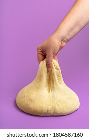 Bread Dough Isolated On A Seamless Purple Background. Woman Hand Stretching The Leavened Dough. Handmade Doughnut Batter. Uncooked Pizza Dough.