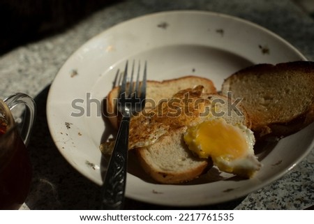 Bread and egg on plate. Breakfast on table. Details of ordinary food. Fork and plate in kitchen. Natural food.
