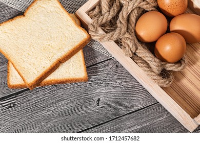 Bread and eggs is in paper trays put on wooden floor background and copy space for text