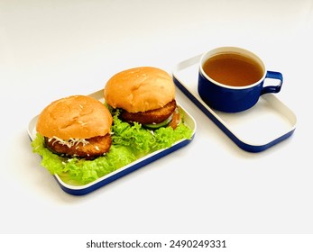 bread filled with lettuce, cucumber, bacon and cheese and a cup of warm ginger water. can be used for food display photos, articles, menu books and other editorial uses. with copy space.Chicken burger